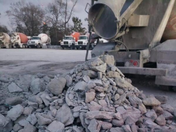 Pile of chipped concrete on the ground beside ready mix concrete trucks